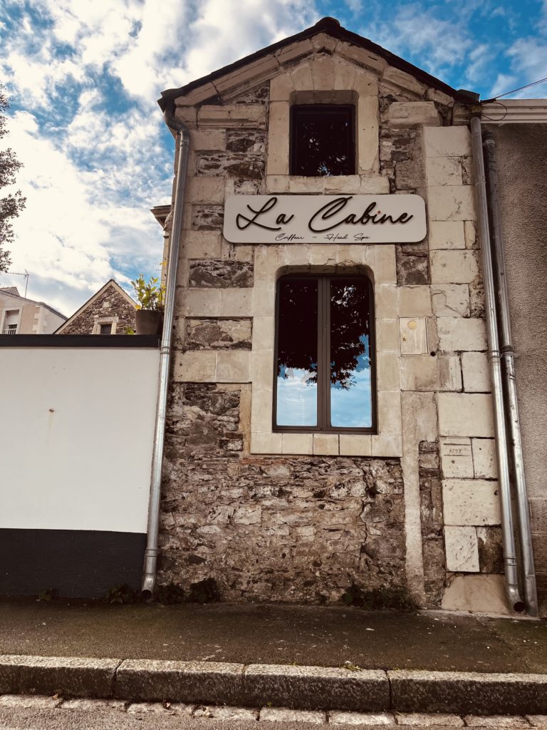 Photographie de l'enseigne du salon de coiffure La Cabine à Chalonnes-sur-Loire.